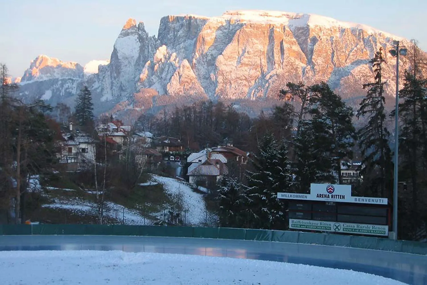 Der Eisring der Arena Ritten im Winter, dahinter leuchtet der Schlern in der Abendsonne