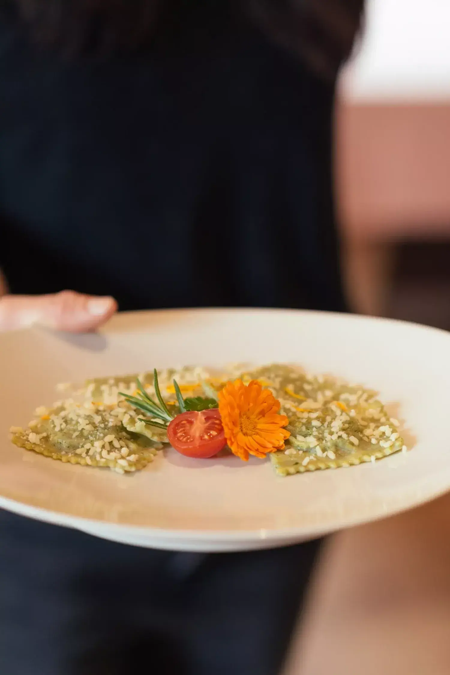 Teller mit hausgemachten Spinatravioli, Parmesan, Rosmarin und einer Ringelblume