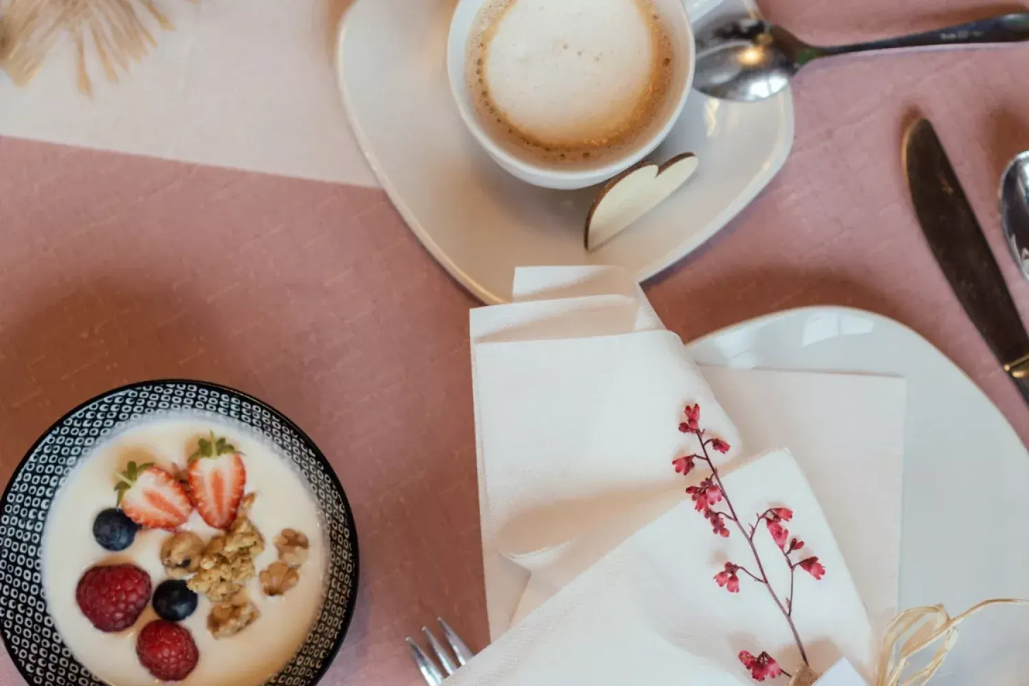 Frühstück von oben: Joghurt mit Beeren und Granola, Cappuccino, Leinenserviette