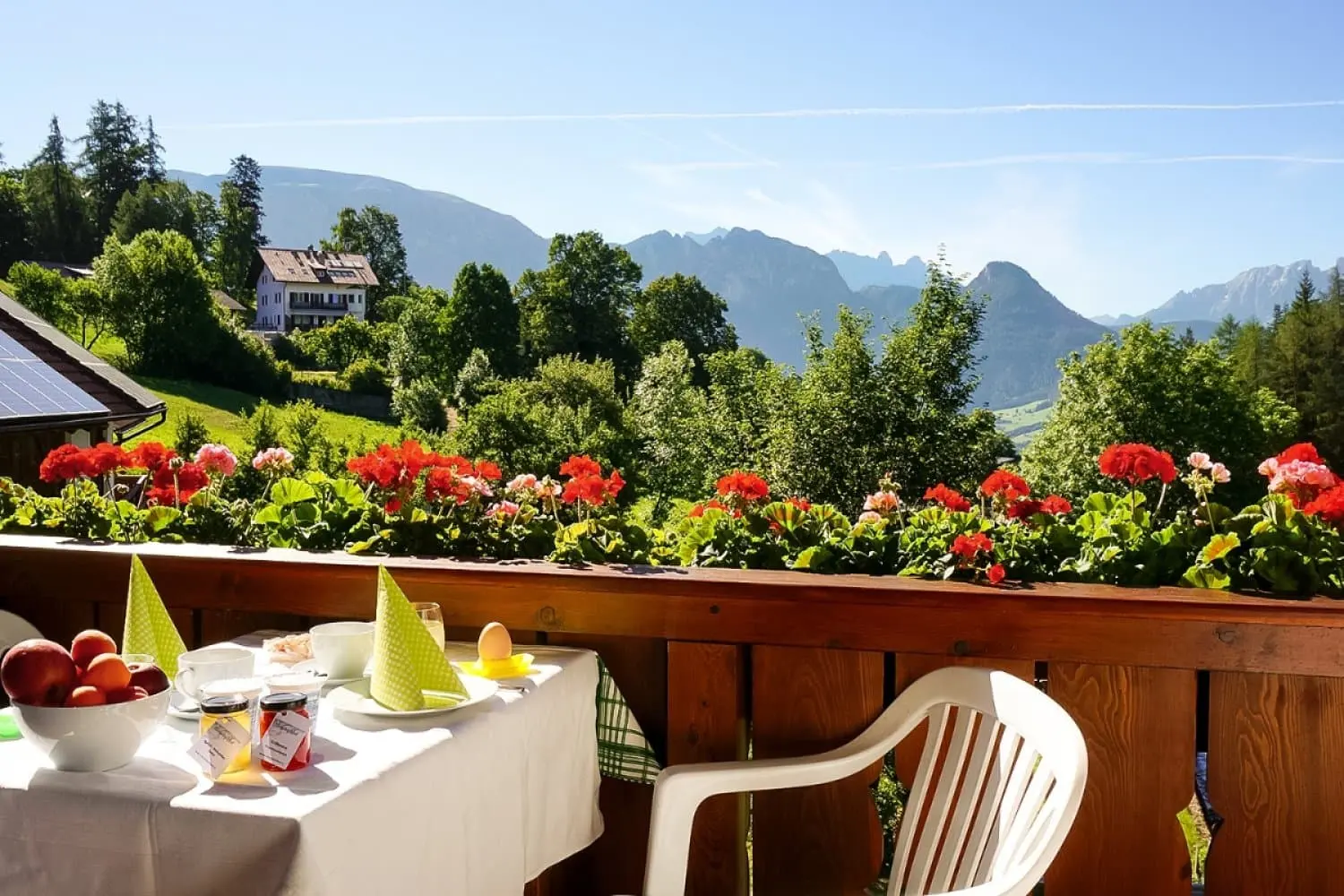 Frühstückstisch auf dem Geranien-Balkon des Moosbachhofs, dahinter die Dolomiten