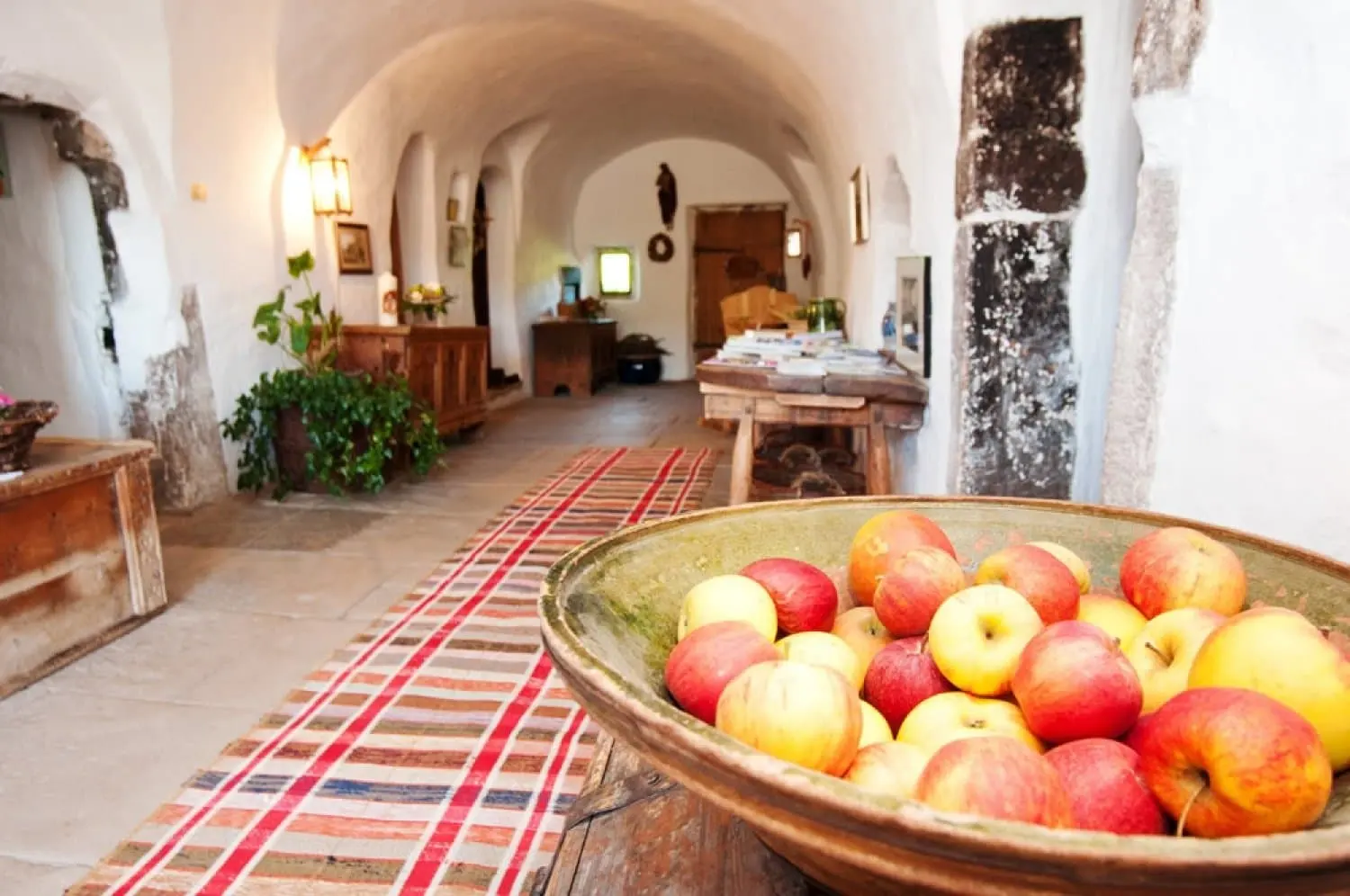 Gewölbegang des Ronacherhofs mit einer großen Kupferschale voller Äpfel