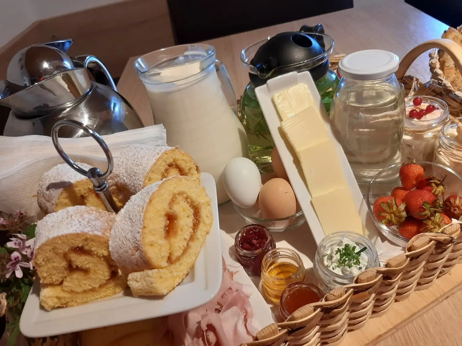 Zwei kleine Gläser Honig neben Marmelade und Kräuterquark im Frühstückskorb